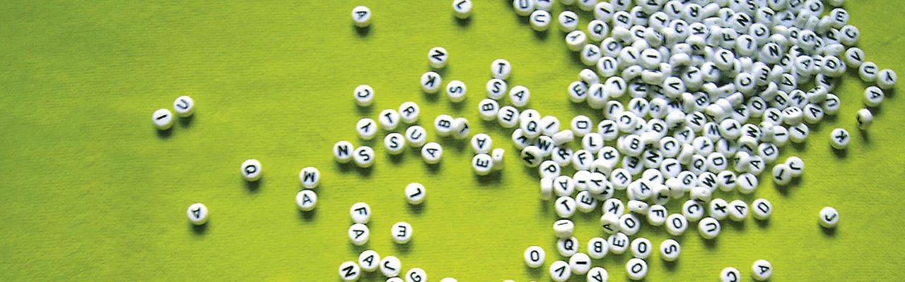 Weiße Buchstabenperlen auf grünem Untergrund